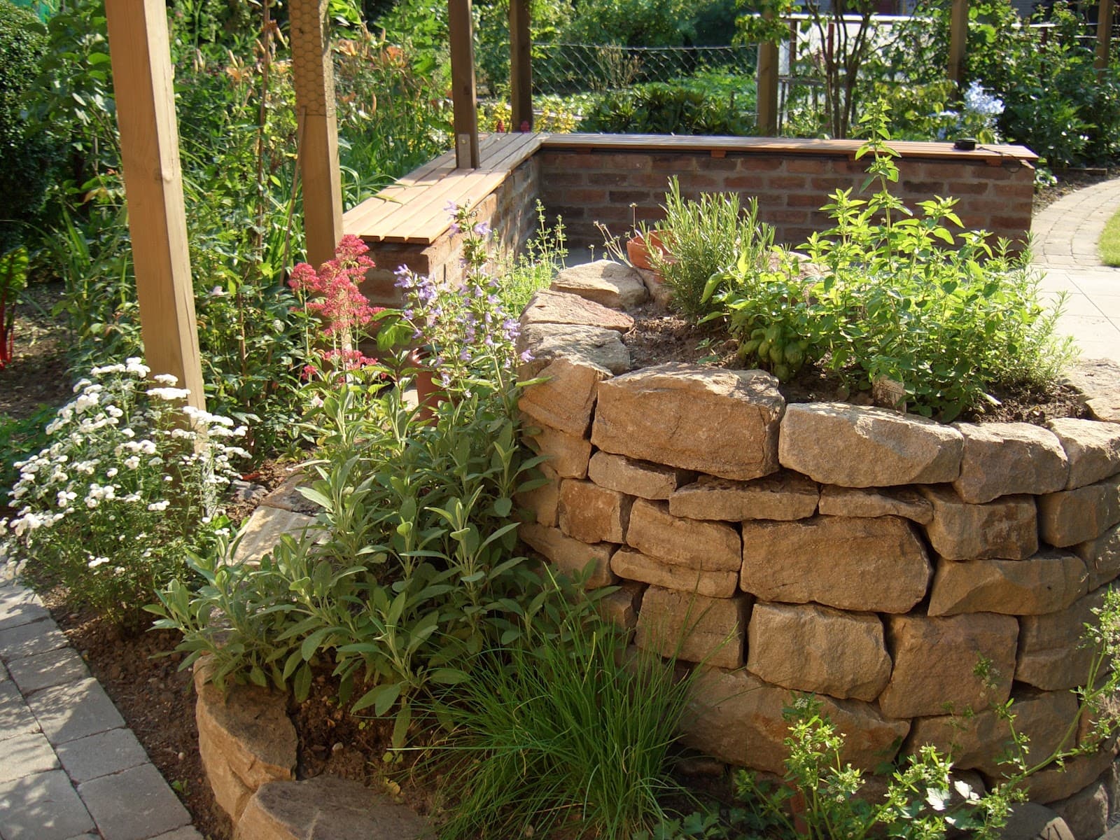 Natursteinmauer mit Staudenbeet und Pergola